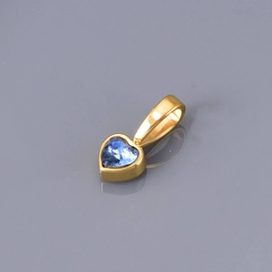 Macro shot of gold-plated heart pendant with centered heart-cut blue zircon gemstone