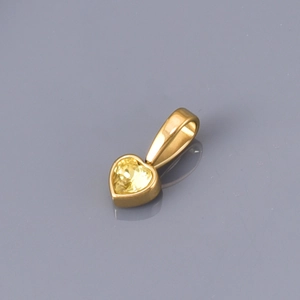 Macro shot of heart-shaped gold pendant with yellow zircon in polished bezel setting