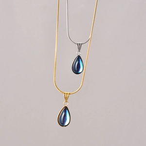 Detail van blauwe traanhangers aan gouden en zilveren slangenketting banden
