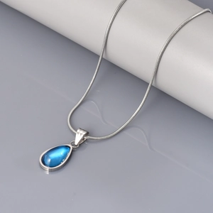 Detail van de waterdruppelvormige blauwe edelsteen hanger aan een zilveren slangenketting