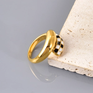 Detailansicht vergoldeter Ring mit Emaille-Schachbrettmuster auf Naturstein