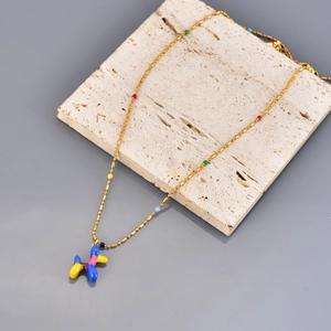 Golden balloon dog pendant necklace with colorful beads on a premium stone background