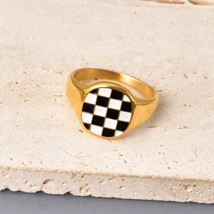 Nahaufnahme des goldenen Schachbrett-Rings auf Stein mit Emaillemuster und Glanzfinish