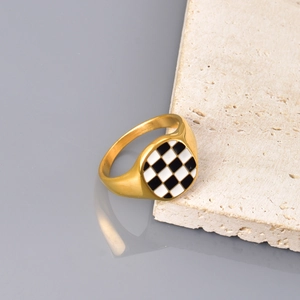 Detailansicht eines goldenen Herz-Siegelrings mit schwarz-weißem Schachbrettmuster