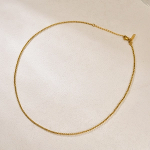 Détail du collier en chaîne dorée montrant le fermoir mousqueton et la chaînette