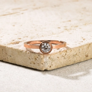 Macro di un anello placcato oro rosa 18k con zircone rotondo su supporto in pietra
