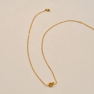 Close-up of a gold-plated knot pendant necklace with fine chain and lobster clasp