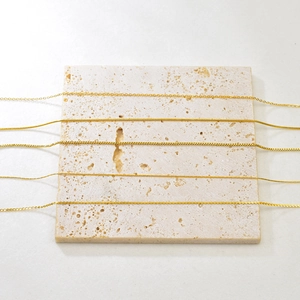 Adjustable gold stainless steel necklace chains in assorted styles on beige stone