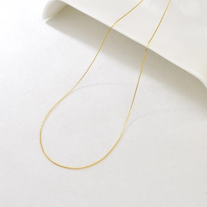 Detailed view of adjustable golden stainless steel necklace on a white ceramic tray