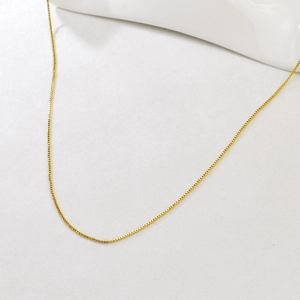 Detailed close-up of a minimalist adjustable golden box chain necklace on white background