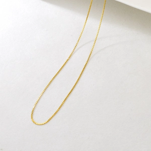 Close-up of adjustable golden stainless steel twist chain necklace with shimmering texture