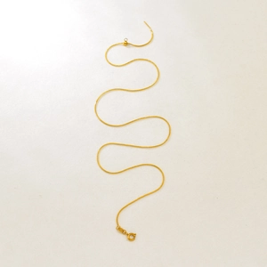 Detail of adjustable gold snake chain featuring a sliding bead and spring ring clasp