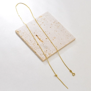 Detail of adjustable gold box chain necklace with lobster clasp and slider ball