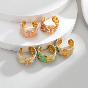 Five gold-plated geometric open rings with colorful drip oil enamel patterns set on a white stand