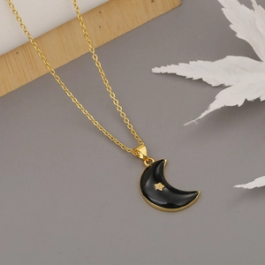 Collar de media luna dorada con esmalte negro y detalle de estrella sobre fondo gris