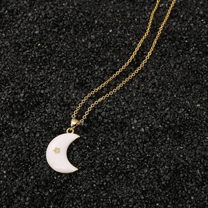 Detalle del colgante de media luna dorada con esmalte blanco y pequeña estrella de oro