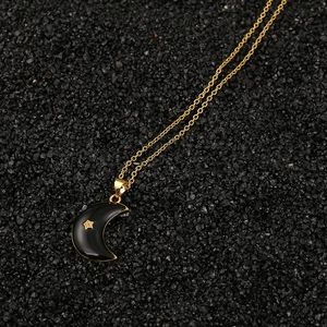 Primer plano de un collar dorado con colgante de luna creciente negra y estrella