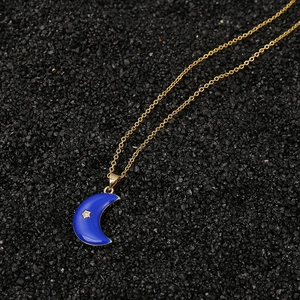 Detalle del colgante de luna dorada con esmalte azul y estrella en superficie oscura