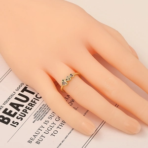 Goldener Herzring mit bunten Zirkoniasteinen an einer Hand auf beigem Hintergrund