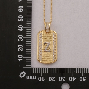 Detalle de colgante hip-hop letra Z dorado con textura trenzada y circonitas sobre una regla