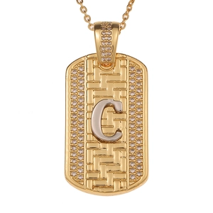 Detalle del colgante de placa dorada con textura tejida y letra C de cristal brillante