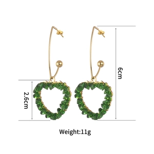 Detail view of gold earrings with green crystal heart pendant including size dimensions