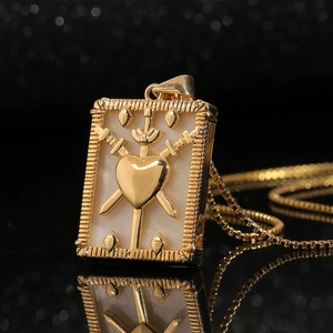 Macro shot of gold sword and heart tarot pendant with pearl shell inlay on box chain