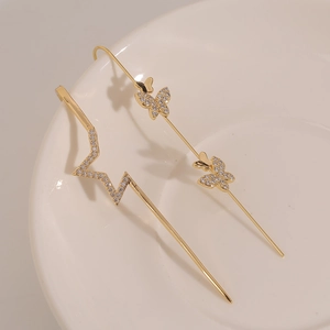 Goldenes Ohrmuschel-Set mit Schmetterlingen und Sternen aus Zirkonia auf weißem Teller
