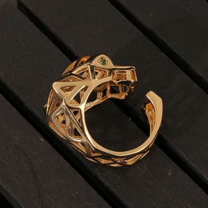 Detailed view of golden leopard ring with geometric hollow design and green stone eyes