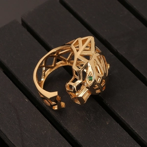Macro view of gold geometric leopard ring with green gemstone eyes and hollow structure