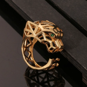 Detailed view of gold geometric hollow leopard ring with green gemstone eyes on wood