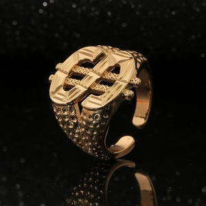 Macro detail of gold-tone hip-hop ring with dollar sign and hammer textured finish