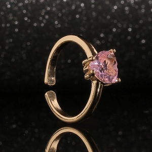 Détail d'une bague dorée avec une pierre rose en cœur sertie de griffes robustes