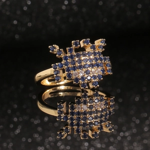 Bague crabe dorée ornée de zircons bleus et blancs sur un fond noir réfléchissant