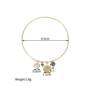 Detail view of 18k gold stainless steel bracelet with pearl and stone charms showing size