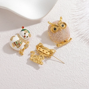 Gros plan de broches chat et hibou avec micro-perles, émail et placage en or 18 carats