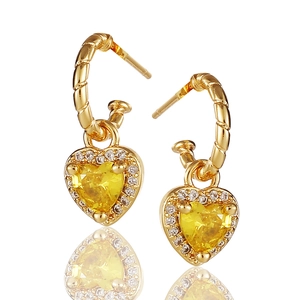 Makro-Detail des vergoldeten Herzohrrings mit gelbem Stein und Mikro-Zirkon-Pavé