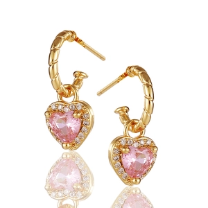 Detail von goldenen Herzohrringen mit rosa Zirkonstein und spiralförmigem Metall