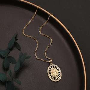 Detail of gold Virgin Mary pendant with cubic zirconia on black matte tray