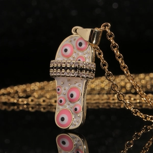 Gouden evil eye slipper hanger ketting met zwart-witte zirkoonstenen op zwarte achtergrond