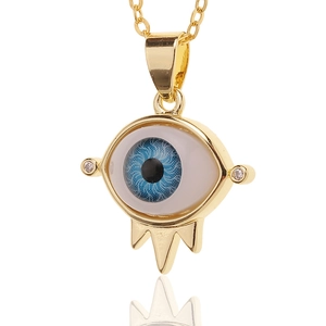 Macro detail of gold plated evil eye pendant with blue ripple iris and cubic zirconia accents