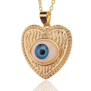 Macro shot of gold-plated heart-shaped evil eye pendant with blue iris and wavy texture