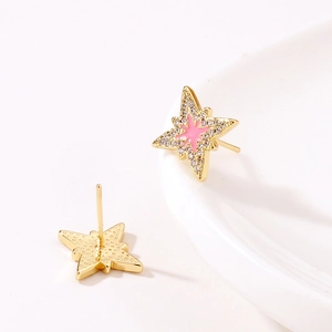 Dettaglio orecchini a stella dorati con smalto rosa e zirconi brillanti incastonati