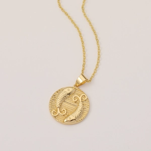 Detailed view of vintage gold-plated circular Pisces zodiac pendant and fine chain