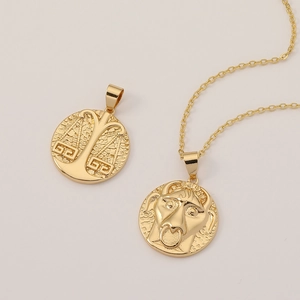 Vintage 18K gold plated Libra and Taurus zodiac medallion necklaces on beige background