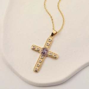 Dettaglio del ciondolo a croce placcato oro 18K con cristalli viola su supporto bianco