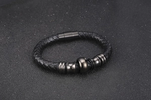 Close-up of black braided leather men's bracelet with dark metal beads and magnetic clasp