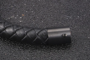 Macro detail of men's braided leather bracelet with matte black magnetic steel clasp