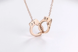 Macro detail of rose gold handcuffs pendant with zircon accents and minimalist chain link
