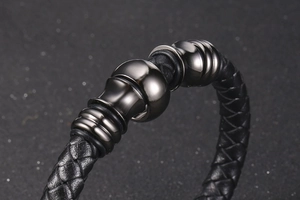 Detail shot of men's braided black leather bracelet with three gunmetal metallic beads